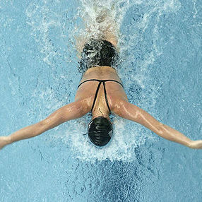 Woman swimming butterfly shot from above.